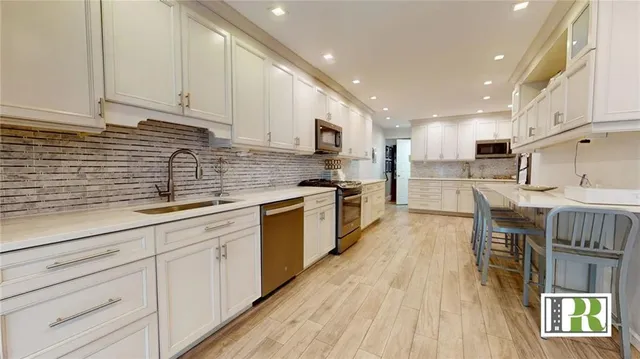 a kitchen with kitchen island granite countertop a sink a counter top space stainless steel appliances and cabinets