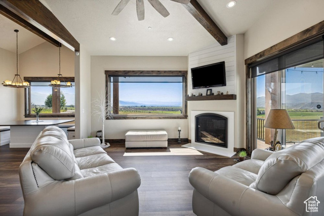 6117 North Rocky Ridge Road Peoa, UT 84061 - Photo 32 of 83 Living room featuring ceiling fan with notable chandelier, a large fireplace, dark hardwood / wood-style flooring, and lofted ceiling with beams