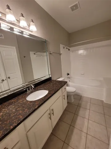 a bathroom with a granite countertop sink a toilet and a mirror