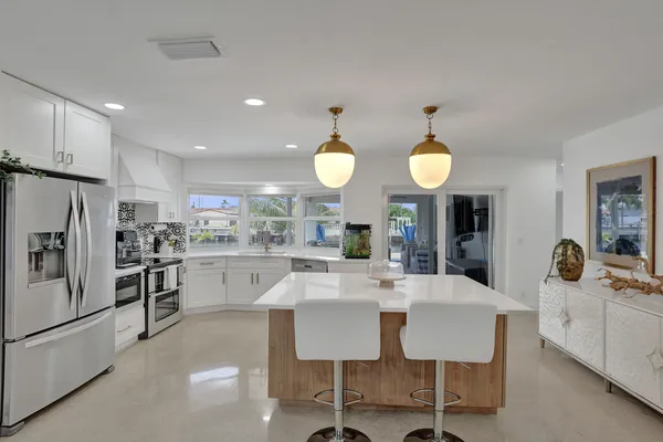 a kitchen with kitchen island granite countertop a sink a stove cabinets and wooden floor