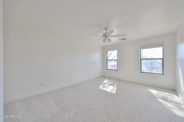 a view of an empty room with chandelier fan