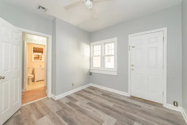 a view of empty room with wooden floor and fan
