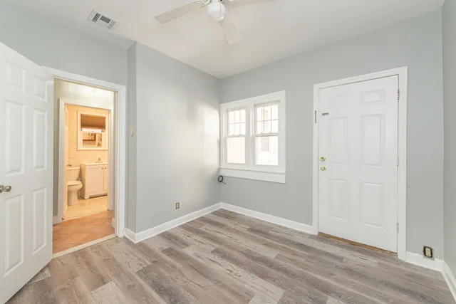 a view of empty room with wooden floor and fan