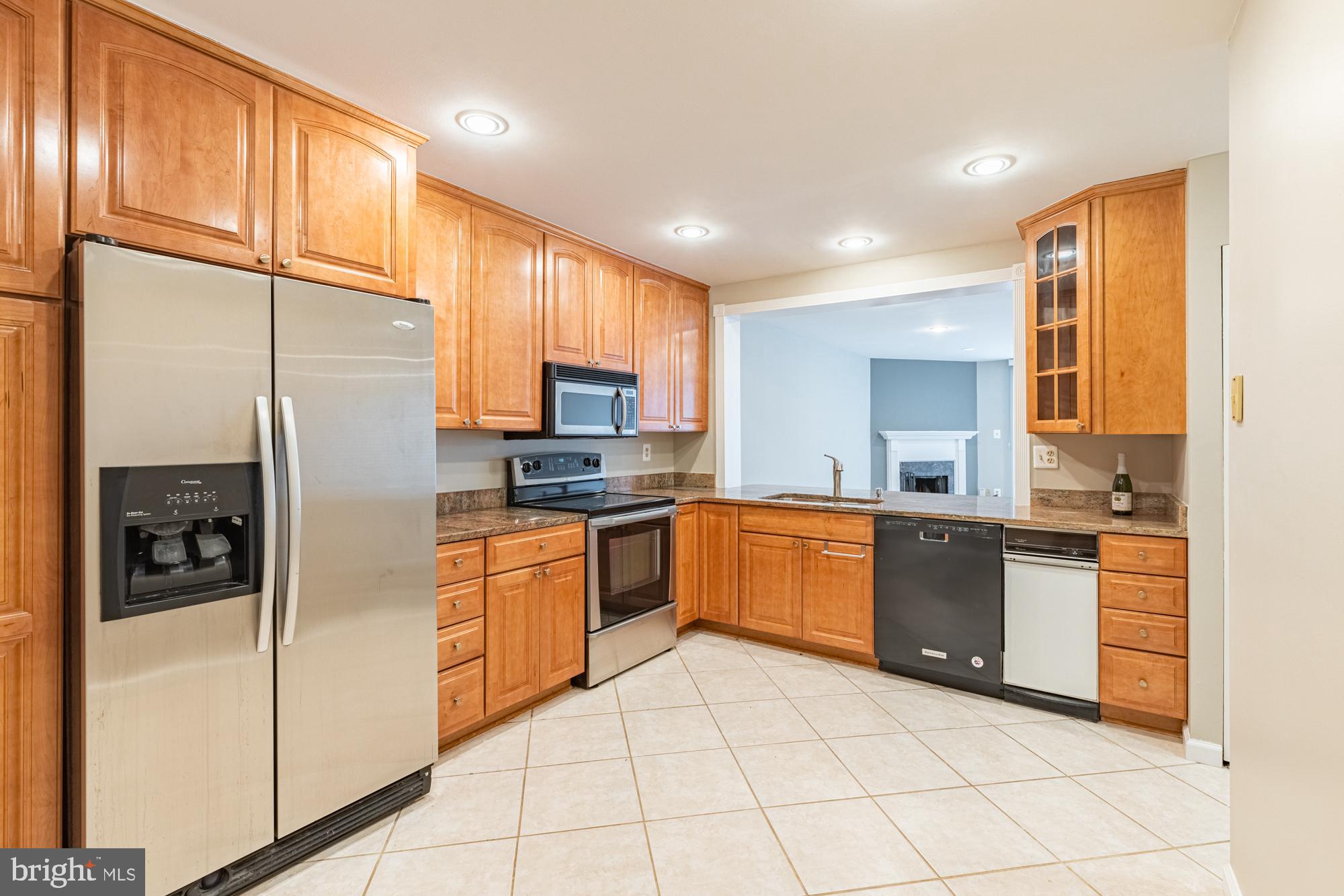 a large kitchen with stainless steel appliances granite countertop a refrigerator a sink dishwasher a oven with granite countertops and cabinets