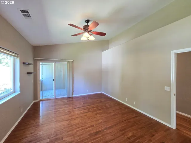 a view of an empty room with window and wooden floor