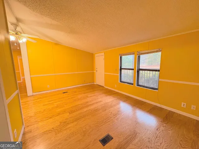 a view of an empty room with a window and wooden floor
