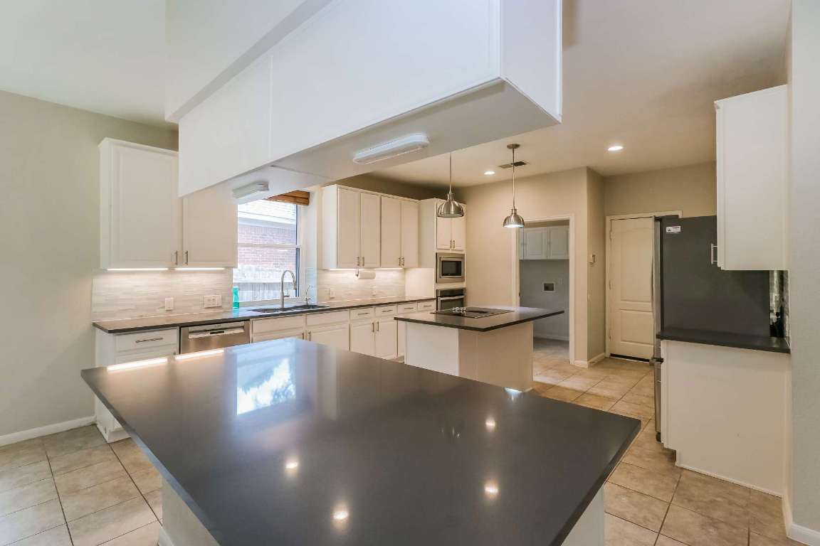 a large kitchen with stainless steel appliances a large counter top and a stove