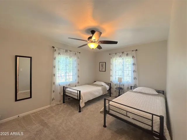 a spacious bedroom with two beds chandelier and a window