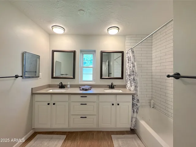 a bathroom with a double vanity sink a mirror and a bathtub
