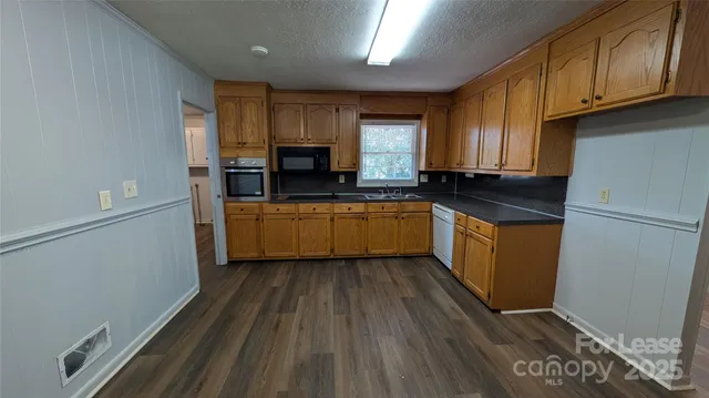 a kitchen with kitchen island granite countertop wooden cabinets a sink a stove and a refrigerator