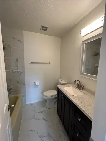 a bathroom with a granite countertop sink a toilet and a mirror