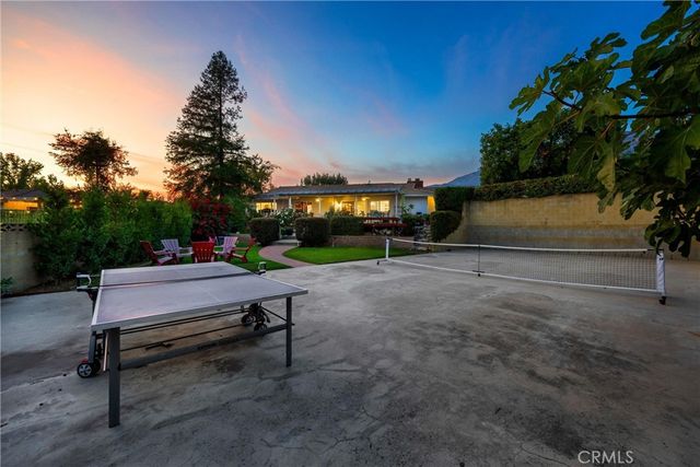 a view of a white house next to a yard with big trees