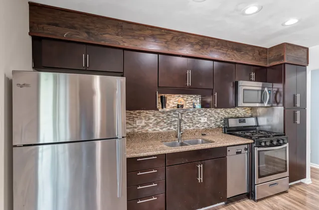 a kitchen with stainless steel appliances granite countertop a refrigerator a stove and a sink