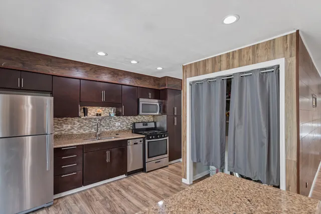 a kitchen with stainless steel appliances kitchen island granite countertop a refrigerator and a stove