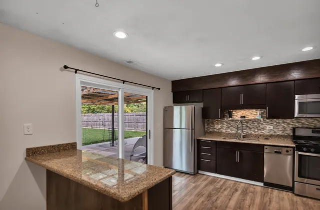 a kitchen with stainless steel appliances granite countertop a refrigerator a stove and a sink