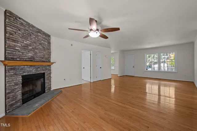 a view of an empty room with wooden floor and a fireplace