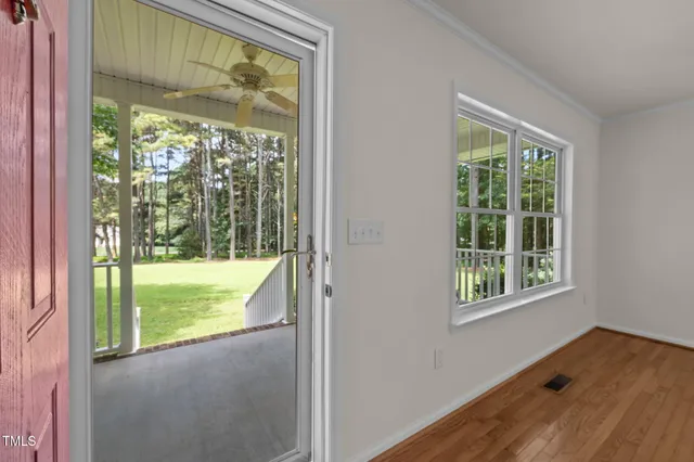 a view of an empty room with wooden floor and a fireplace