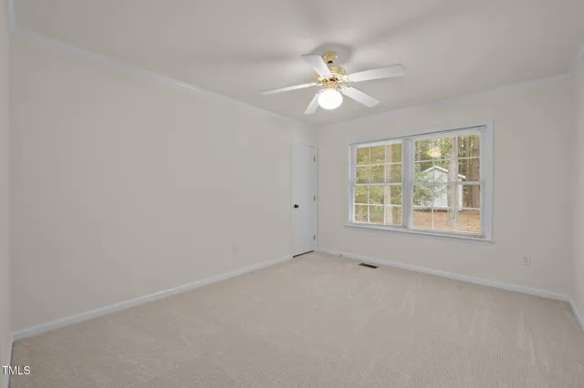 an empty room with a window and a fan