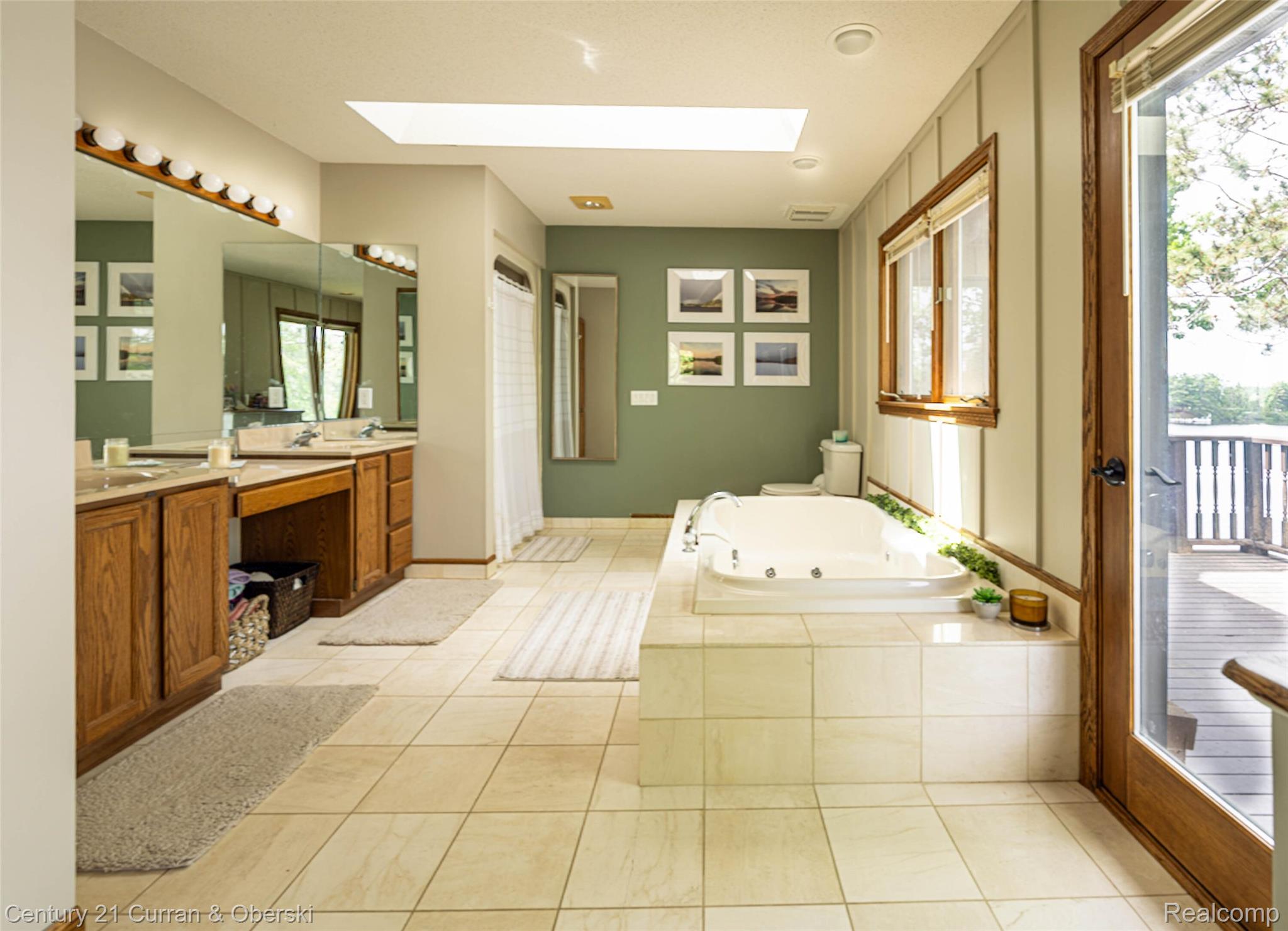 8775 Winding Rdg Drive Millersburg, MI 49759 - Photo 32 of 53 Spacious bathroom featuring a built-in jetted tub, dual vanity with wood cabinetry, and a skylight