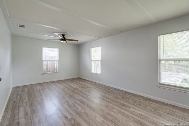 a view of an empty room with a window and wooden floor