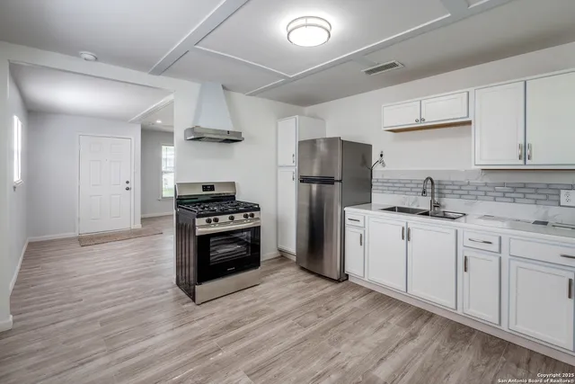 a kitchen with stainless steel appliances a refrigerator sink and stove top oven