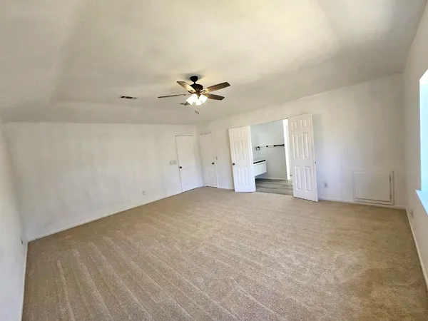 an empty room with chandelier fan and windows