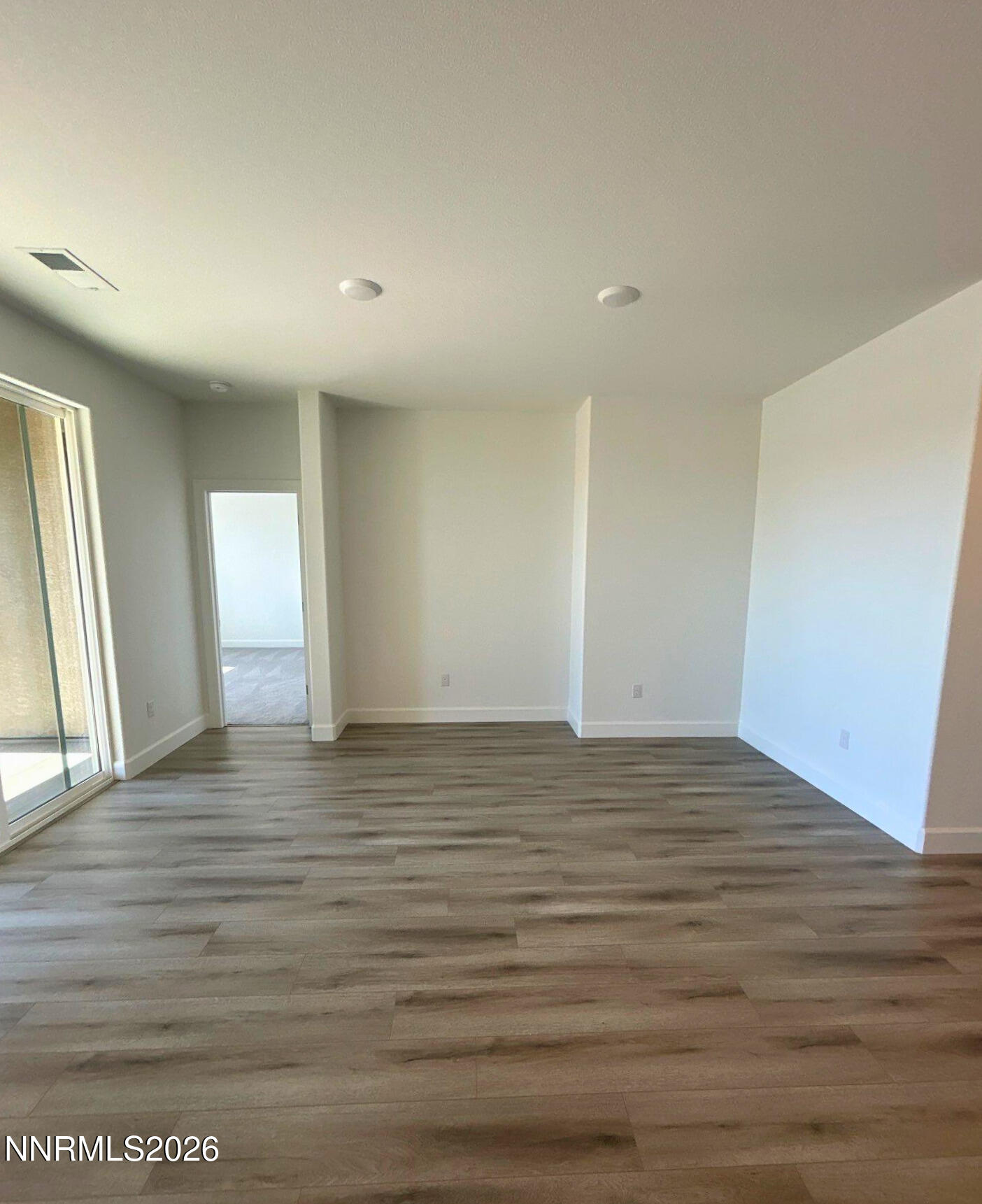 3453 Payton Way Fernley, NV 89408 - Photo 6 of 15 a view of an empty room with wooden floor and window