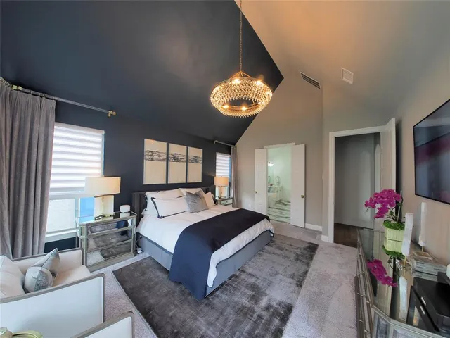 a spacious bedroom with a bed and a chandelier