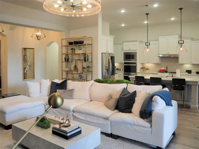a living room with furniture kitchen view and a chandelier