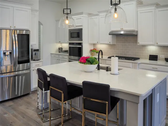 a kitchen with stainless steel appliances granite countertop a table chairs stove microwave and cabinets