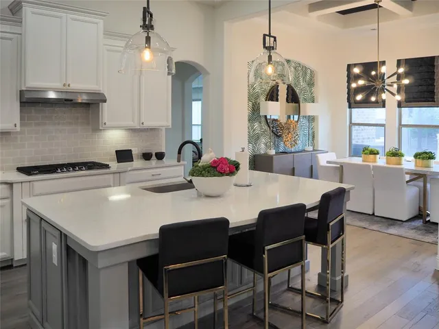 a kitchen with stainless steel appliances granite countertop a stove a refrigerator a sink a dining table and chairs with wooden floor