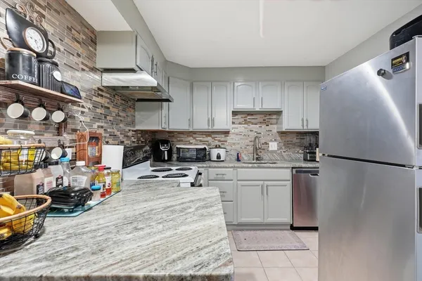 a kitchen with stainless steel appliances granite countertop a refrigerator a stove and a sink