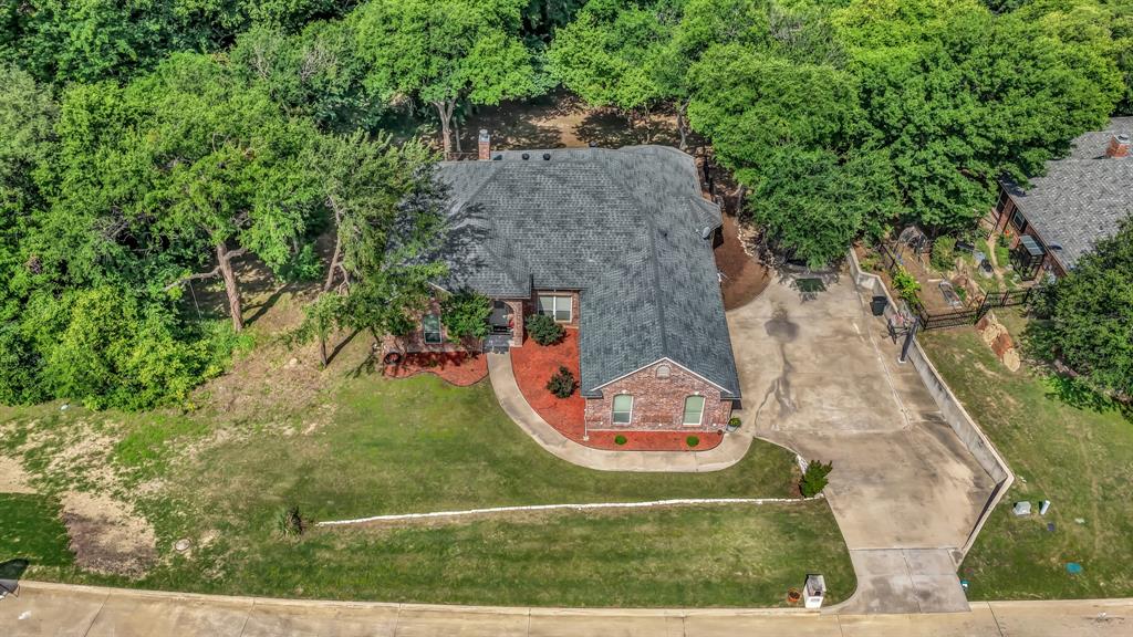 203 Mockingbird Lane Aledo, TX 76008 - Photo 36 of 37 Aerial perspective showcasing a brick residence with a dark shingle roof, a concrete driveway, and mature landscaping