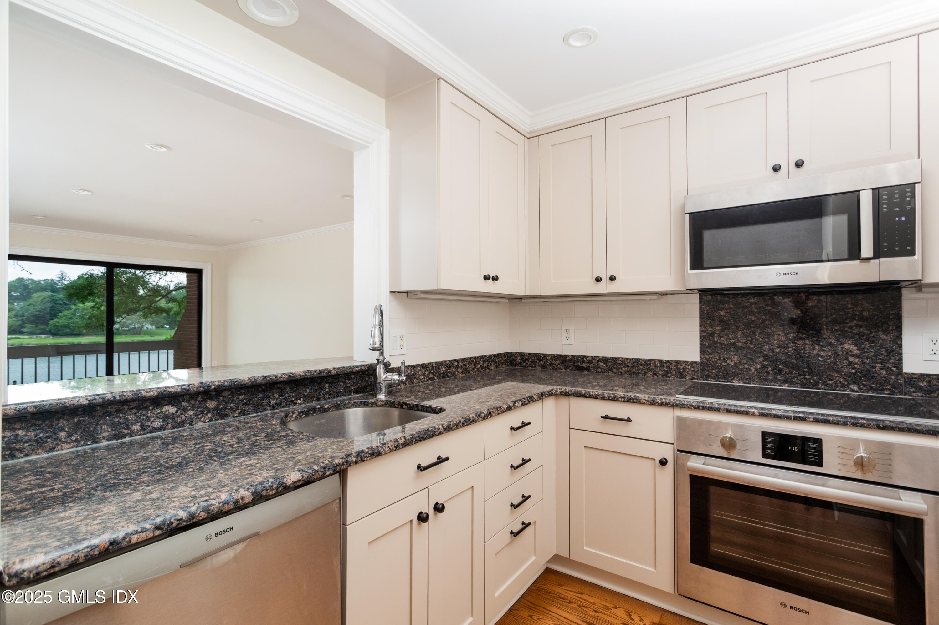15 River Road, Unit 220 Cos Cob, CT 06807 - Photo 9 of 27 a kitchen with granite countertop white cabinets and window