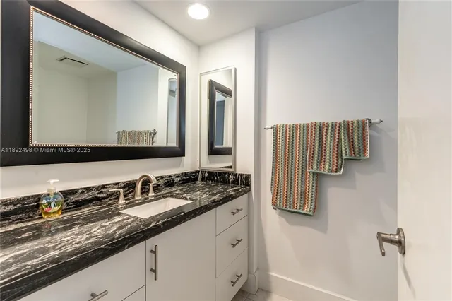 a bathroom with a granite countertop sink and a mirror