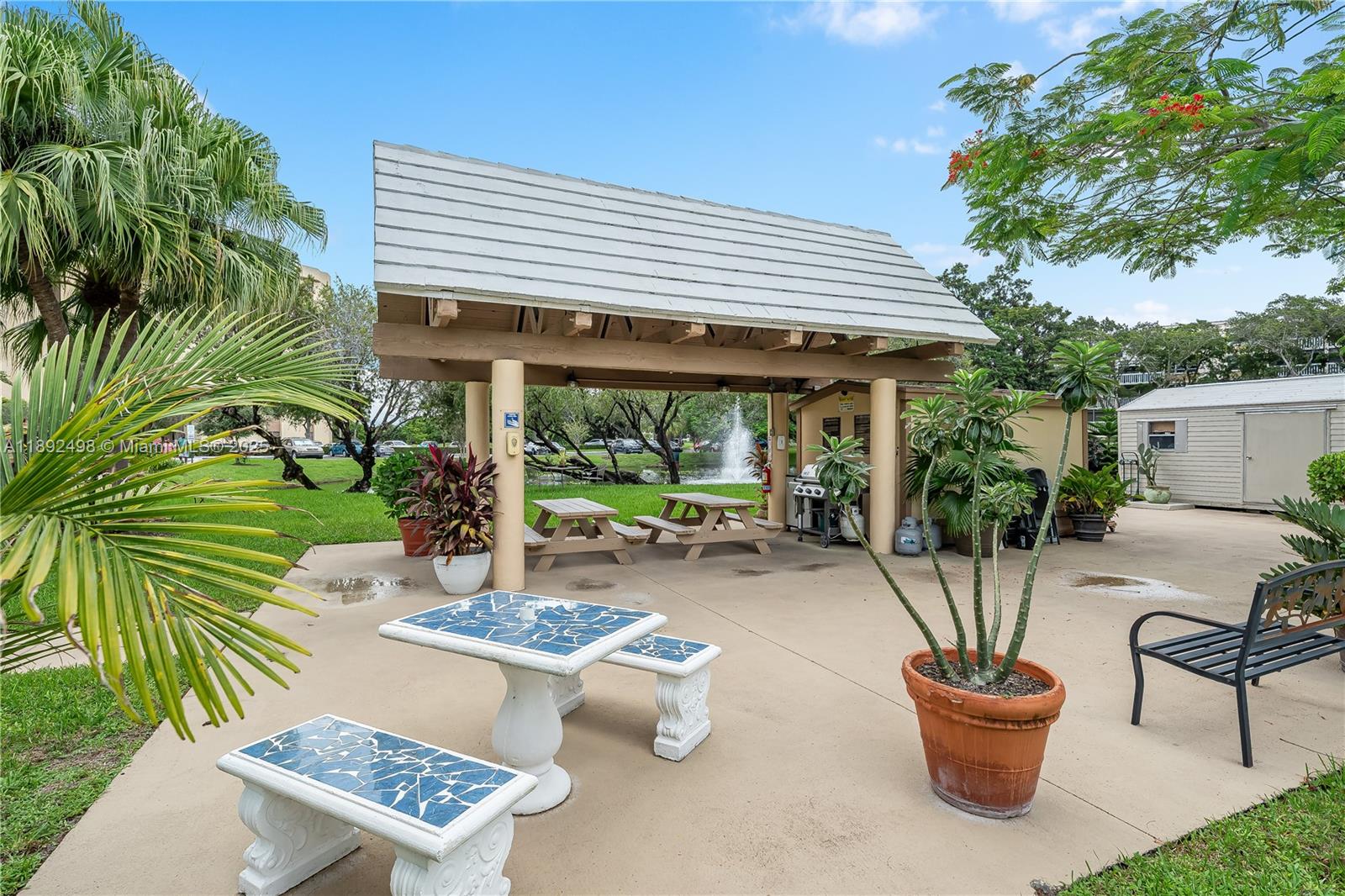 7300 Radice Court, Unit 109 Lauderhill, FL 33319 - Photo 33 of 35 a view of a patio with table and chairs potted plants and palm tree