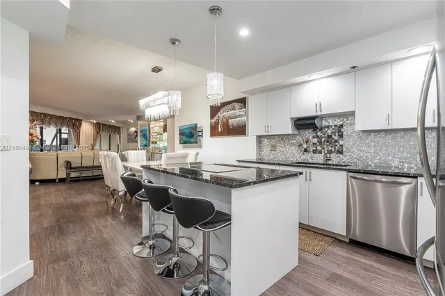 a kitchen with stainless steel appliances granite countertop a stove top oven a sink a dining table and chairs with wooden floor