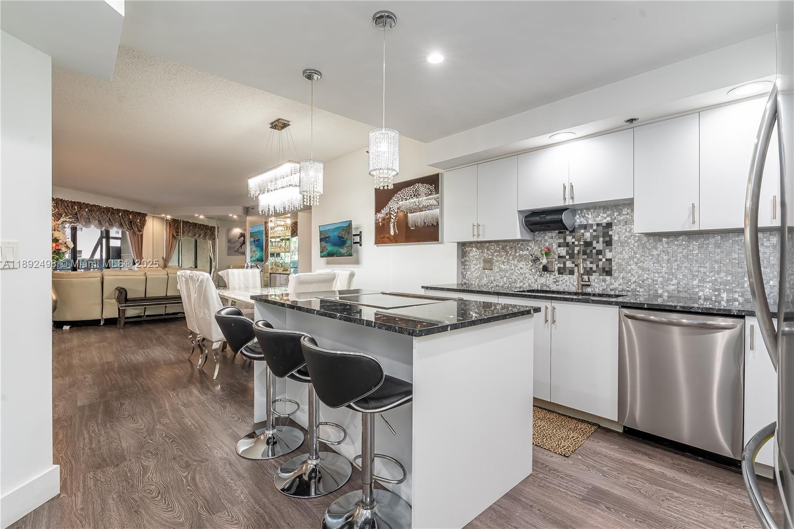 7300 Radice Court, Unit 109 Lauderhill, FL 33319 - Photo 5 of 35 a kitchen with stainless steel appliances granite countertop a stove top oven a sink a dining table and chairs with wooden floor