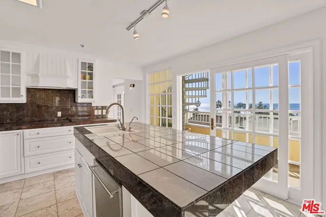 a kitchen with kitchen island granite countertop a table chairs sink and cabinets
