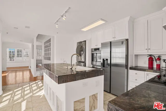 a kitchen with stainless steel appliances granite countertop a sink refrigerator and cabinets