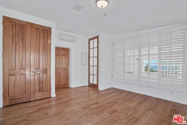 an empty room with wooden floor and windows with curtains