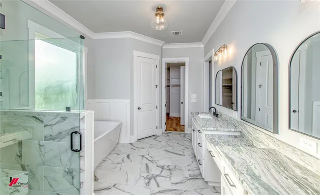 a spacious en suite bathroom with sink glass door and chandelier