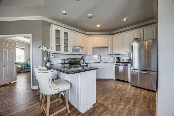 a kitchen with a refrigerator a sink dishwasher a stove and white cabinets with wooden floor