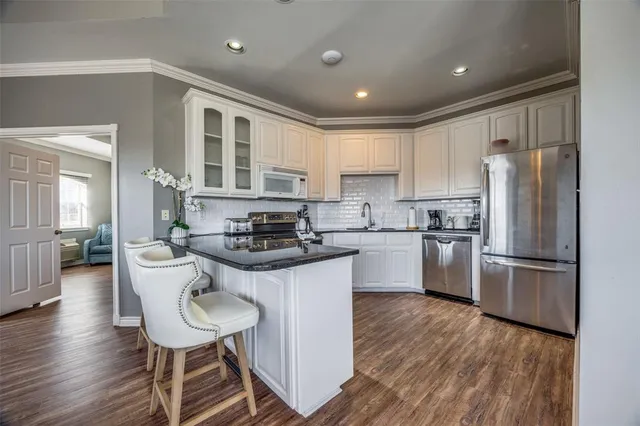 a kitchen with a refrigerator a sink dishwasher a stove and white cabinets with wooden floor