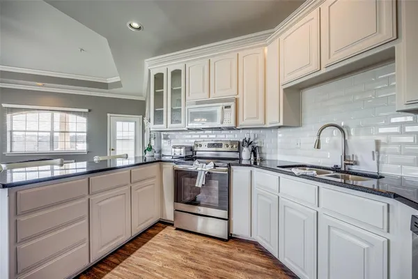 a kitchen with stainless steel appliances granite countertop a sink and cabinets with wooden floors