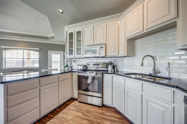 a kitchen with stainless steel appliances granite countertop a sink and cabinets with wooden floors