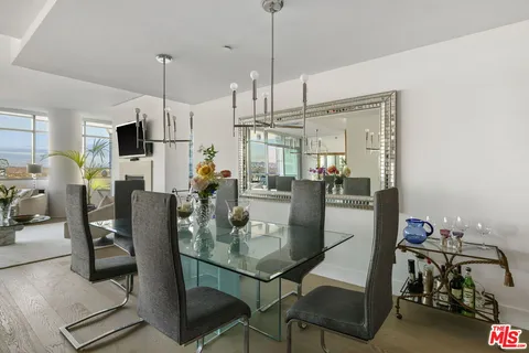 a living room with couches a fireplace and a dining table with wooden floor