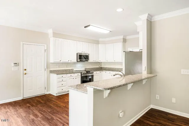 a kitchen with a refrigerator a stove top oven and white cabinets