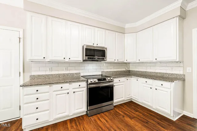 a kitchen with granite countertop white cabinets and black appliances