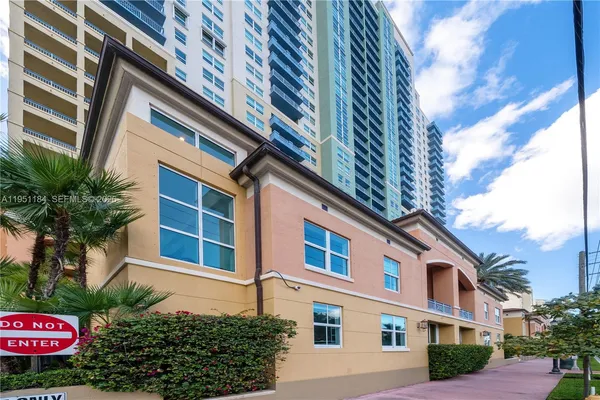 a front view of a multi story residential apartment building with yard and sign board